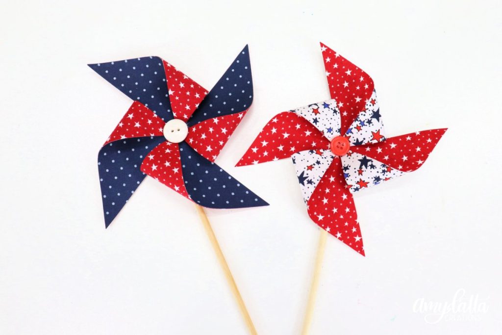 Image contains two fabric pinwheels; one red and blue, and one white and red.
