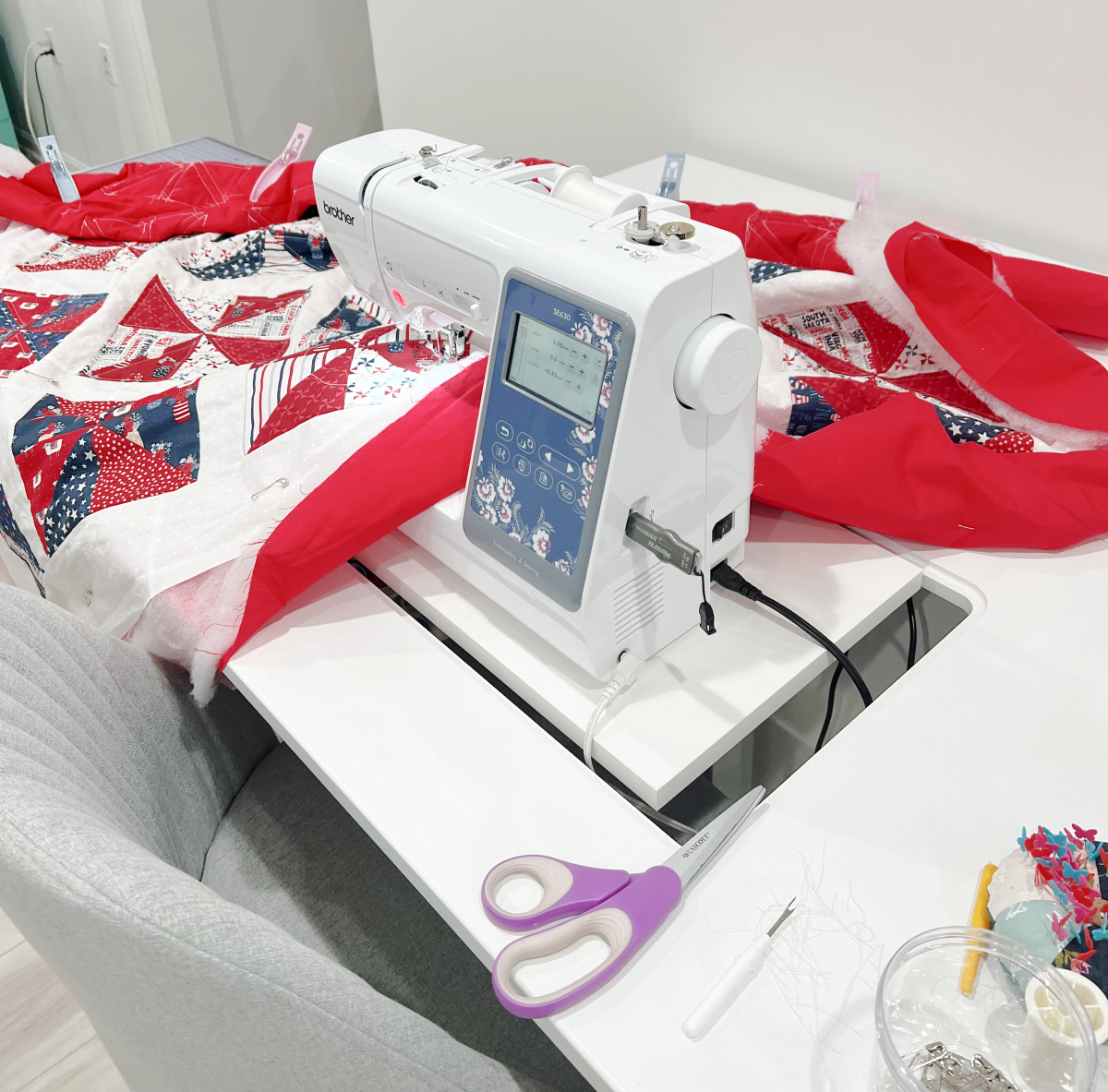 Image contains a sewing machine with an in-progress patriotic quilt spread out around it.