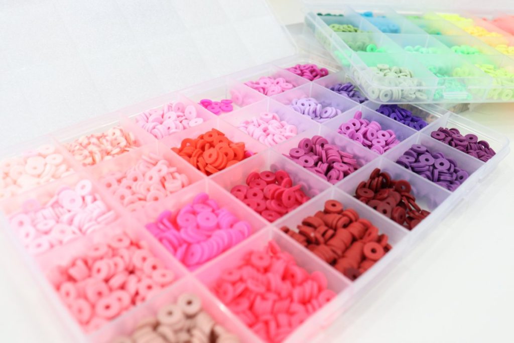 Image contains two plastic divided trays, each containing an assortment of colorful clay beads.