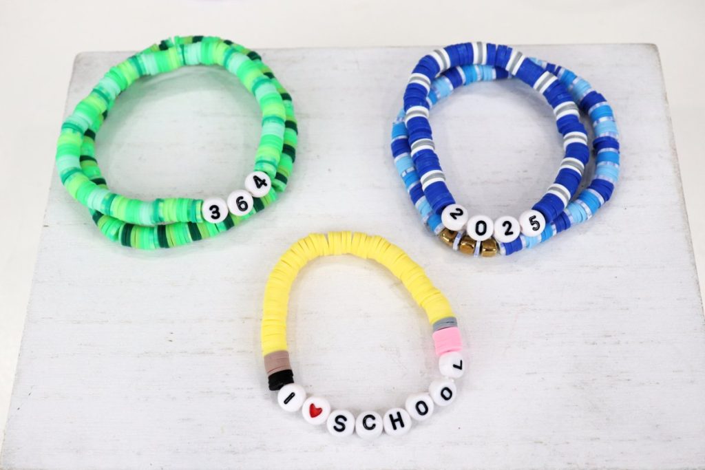 Image contains five clay bead bracelets in a variety of colors on a white background.