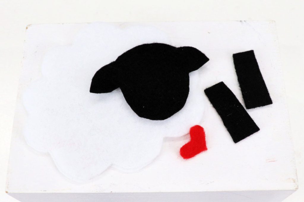 Image contains black, red, and white felt cut into pieces for the sheep project.