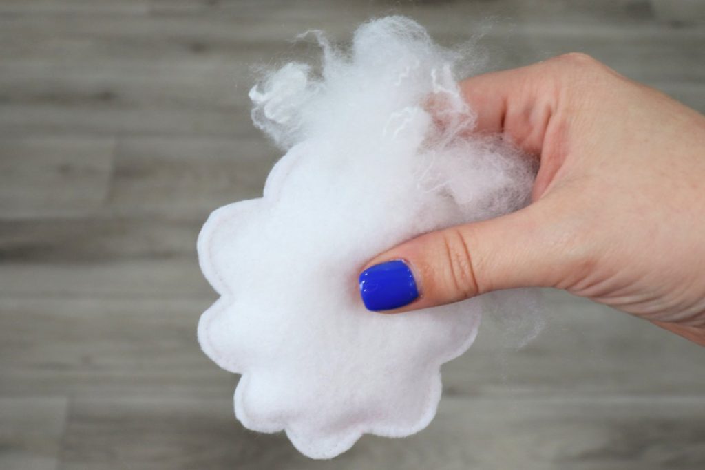 Image contains Amy’s hand stuffing the felt sheep’s body with Poly-Fil.