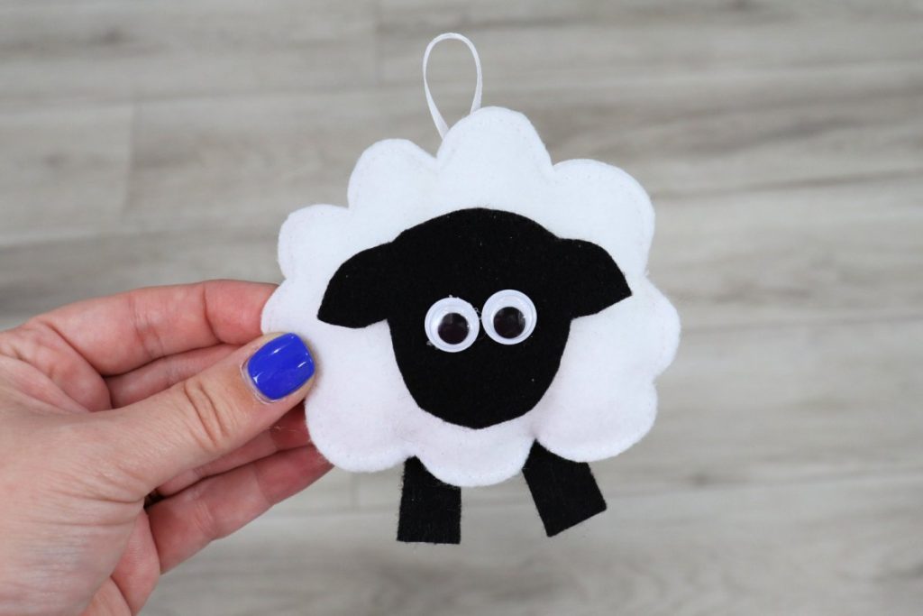 Image contains Amy’s hand holding a small sheep made from felt.
