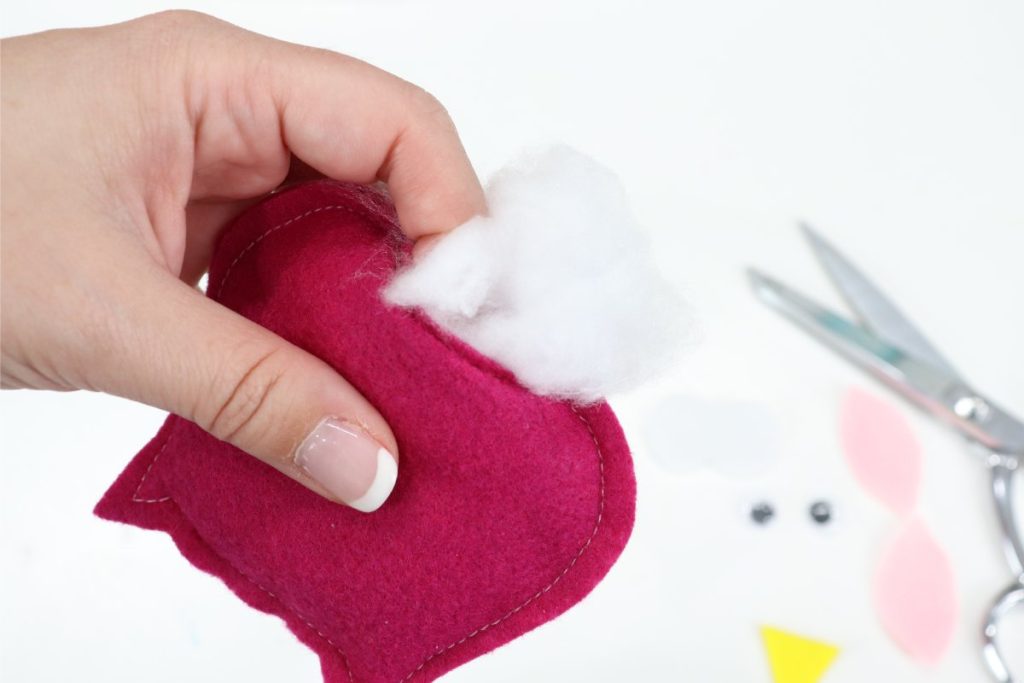 Image contains Amy’s hand pushing Poly-Fil into a pink felt owl’s body.
