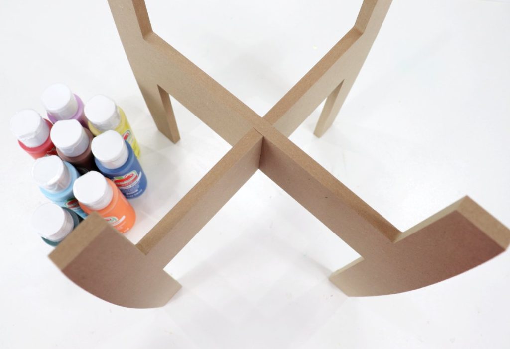Image contains an unpainted brown plant stand with eight bottles of paint nearby.