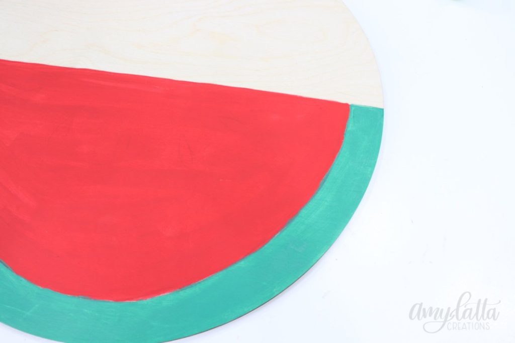 Image contains a large wooden circle. The bottom half is painted red and green.