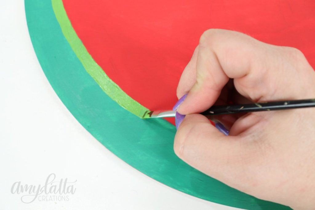 Image contains Amy’s hand painting a light green stripe on the watermelon.