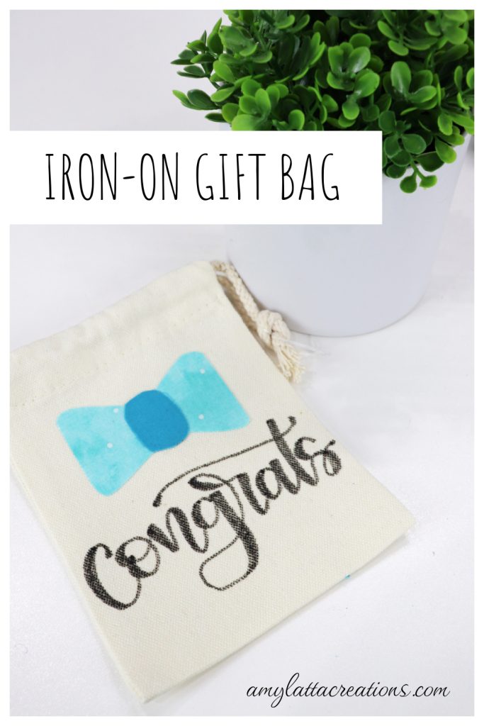 Image contains a small canvas drawstring bag with a blue fabric bow and the written message, “congrats” on a white background. A faux plant sits nearby.