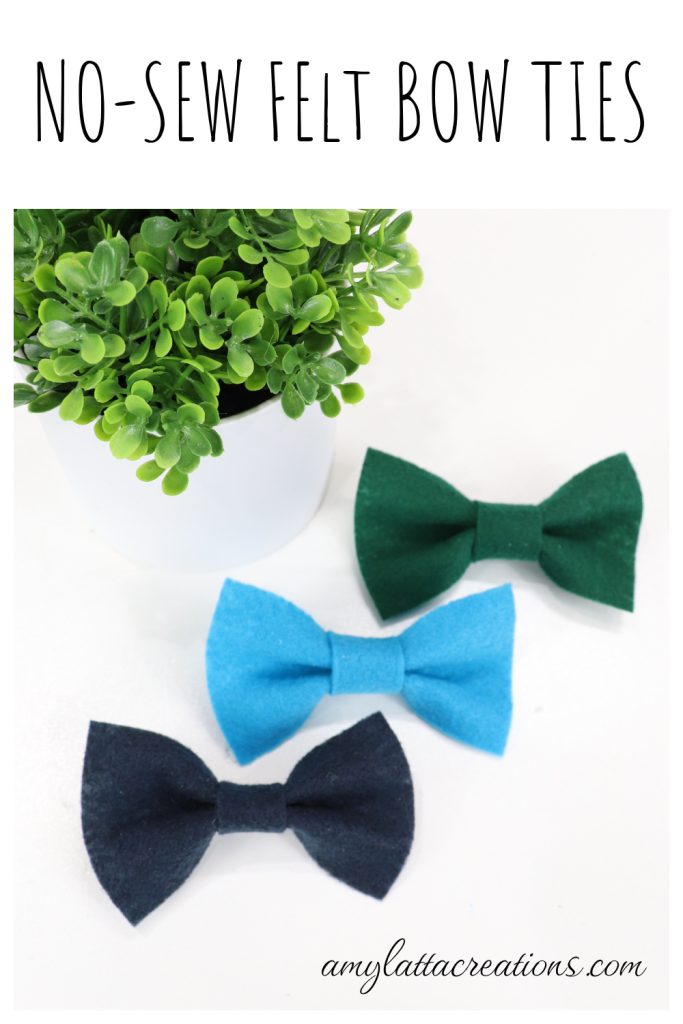 Image contains three felt bow ties; one dark green, one light blue, and one navy, sitting on a white table near a faux plant.
