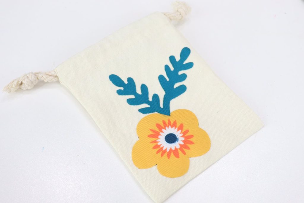Image contains a small canvas bag with a yellow flower and blue leaves ironed on.