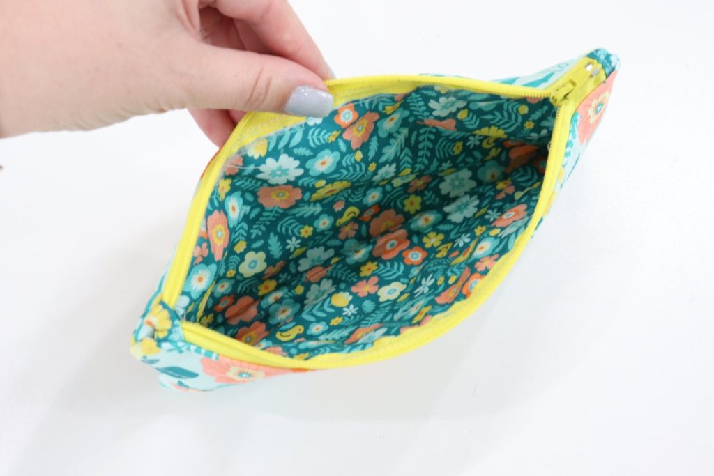 Image contains Amy’s hand holding the pouch open, with a view of the floral lining inside.