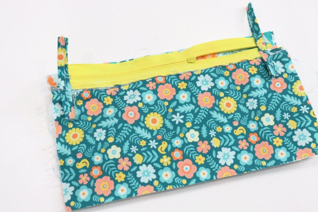 Image contains a yellow zipper on top of the layers of the fabric pouch.