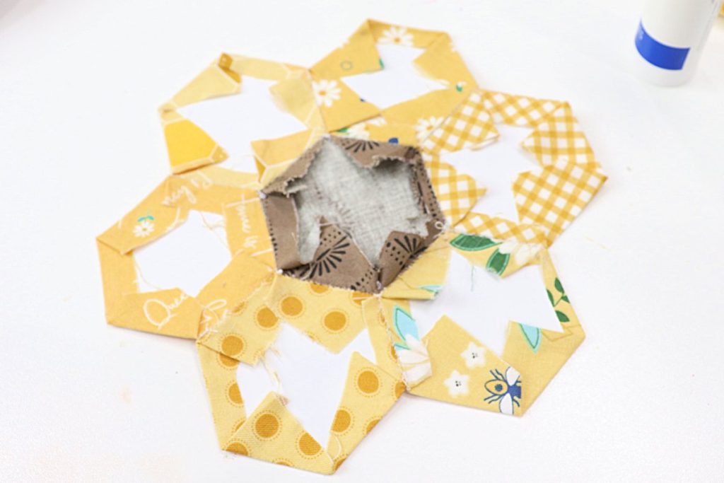 Image contains the back side of a sunflower formed from fabric hexagons, with the white paper shapes visible.