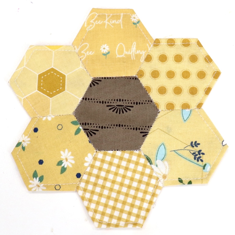 Image is a closeup of the fabric sunflower coaster made from hexagon shapes.
