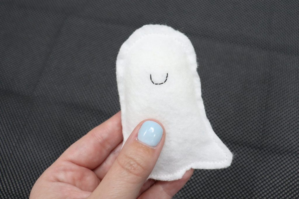 Image contains Amy’s hand holding a felt ghost shape that has been stuffed with Poly-Fil.