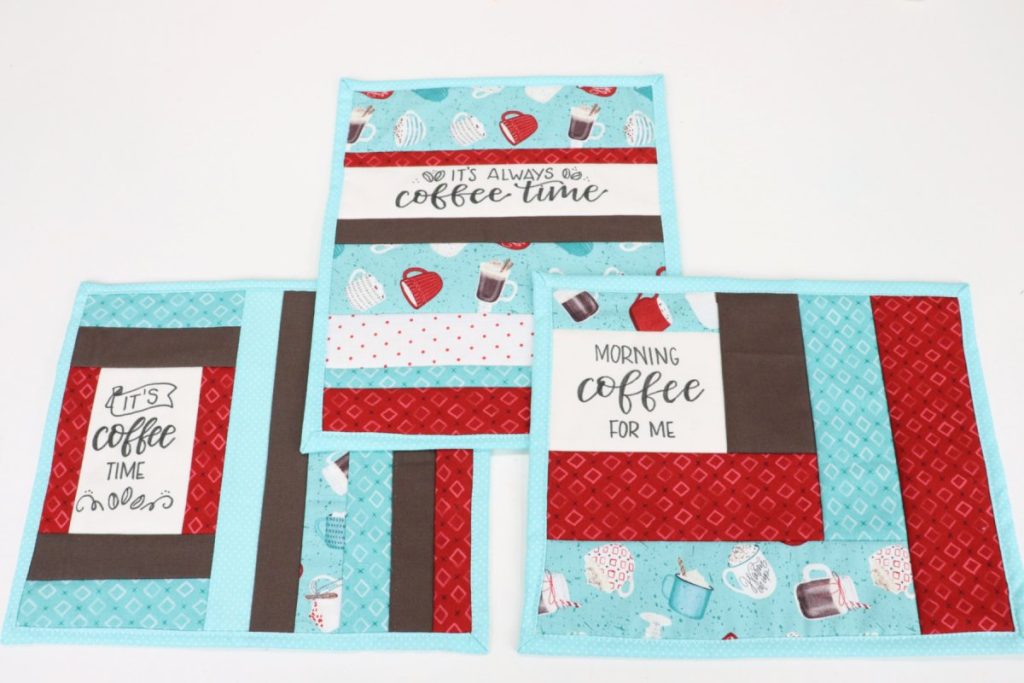 Image contains three quilted mug mats with multicolored coffee themed fabrics.