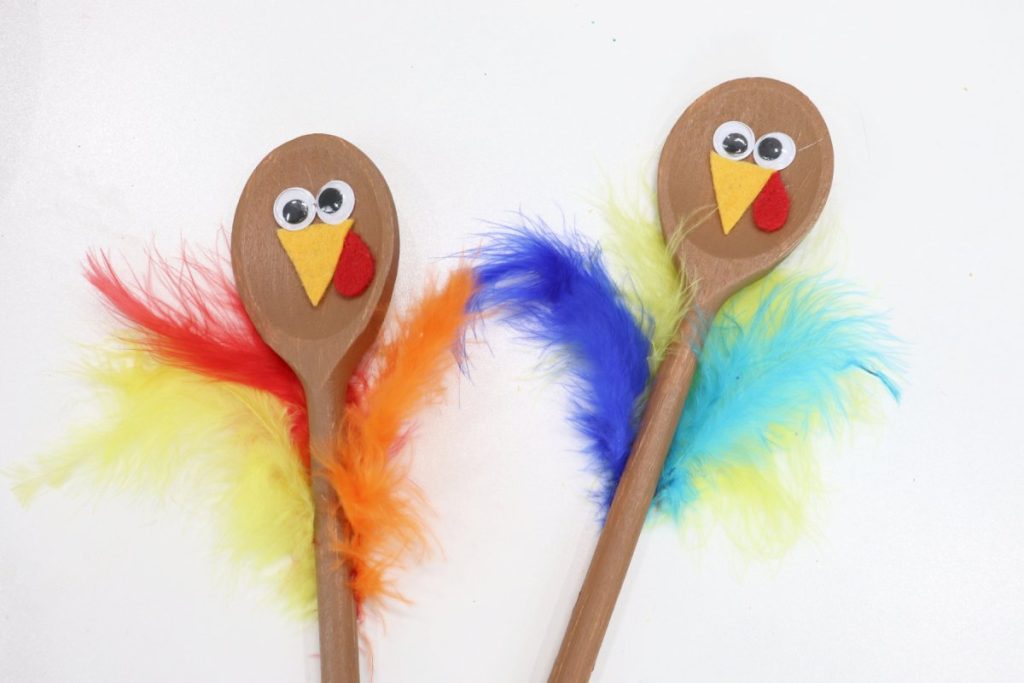 Image contains two wooden spoons turkeys that are painted brown with faces and feathers.
