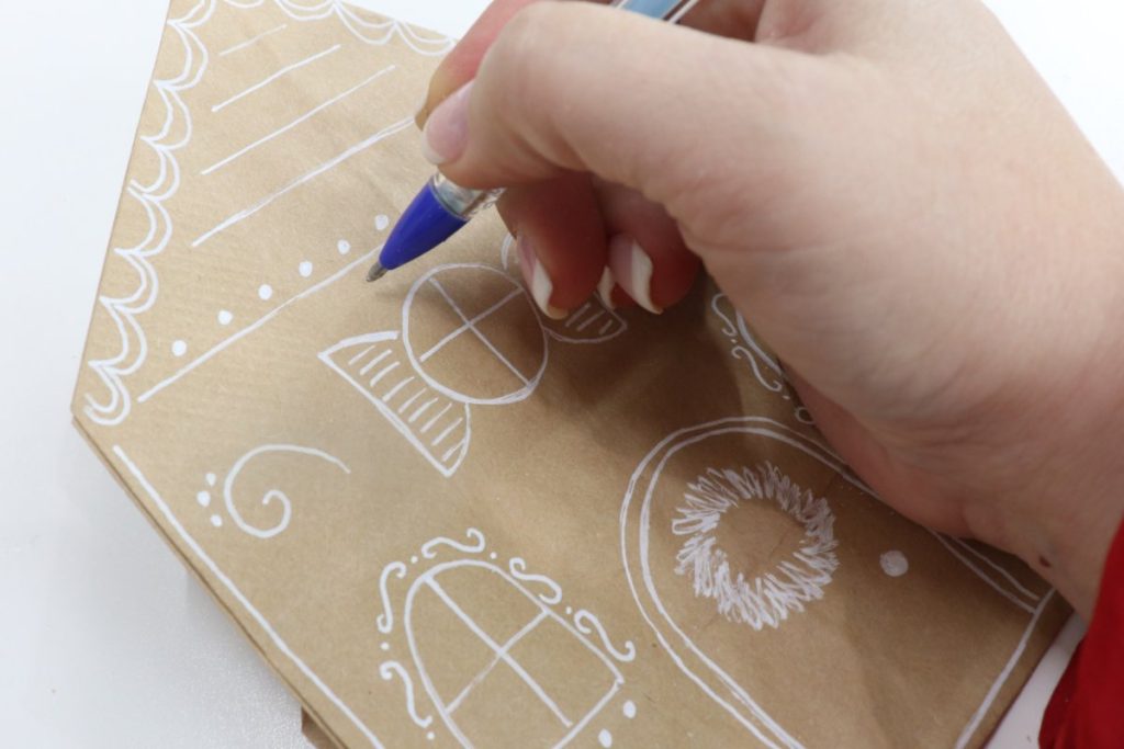 Image contains Amy’s hand applying a glue pen to the decorated paper bag.