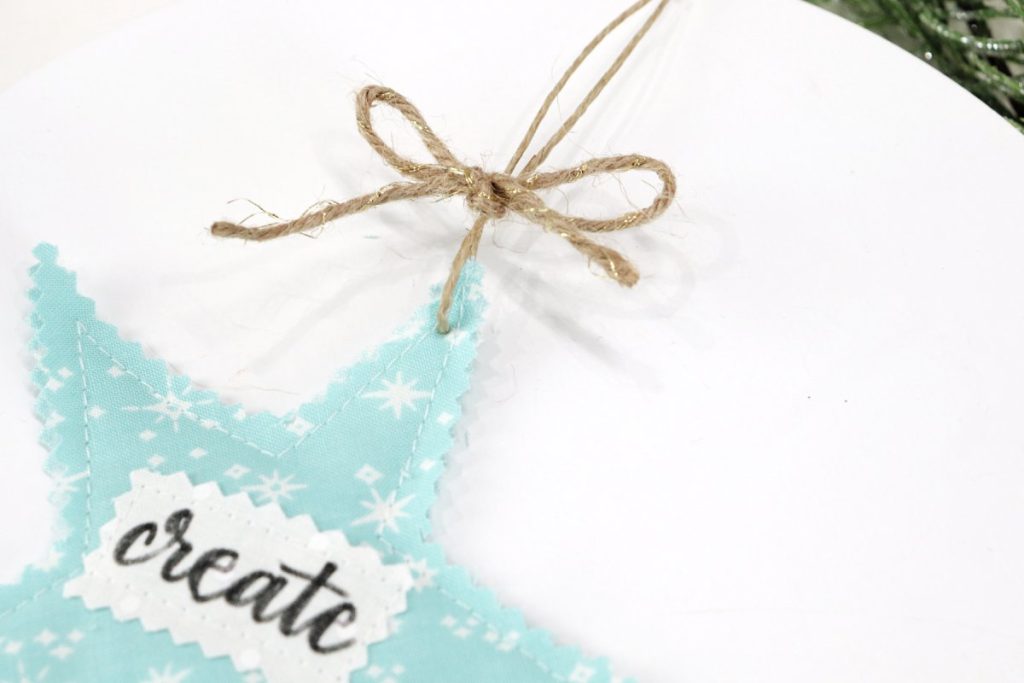Image contains a teal scrappy star with a twine hanger and a twine bow tied around it above the top point.