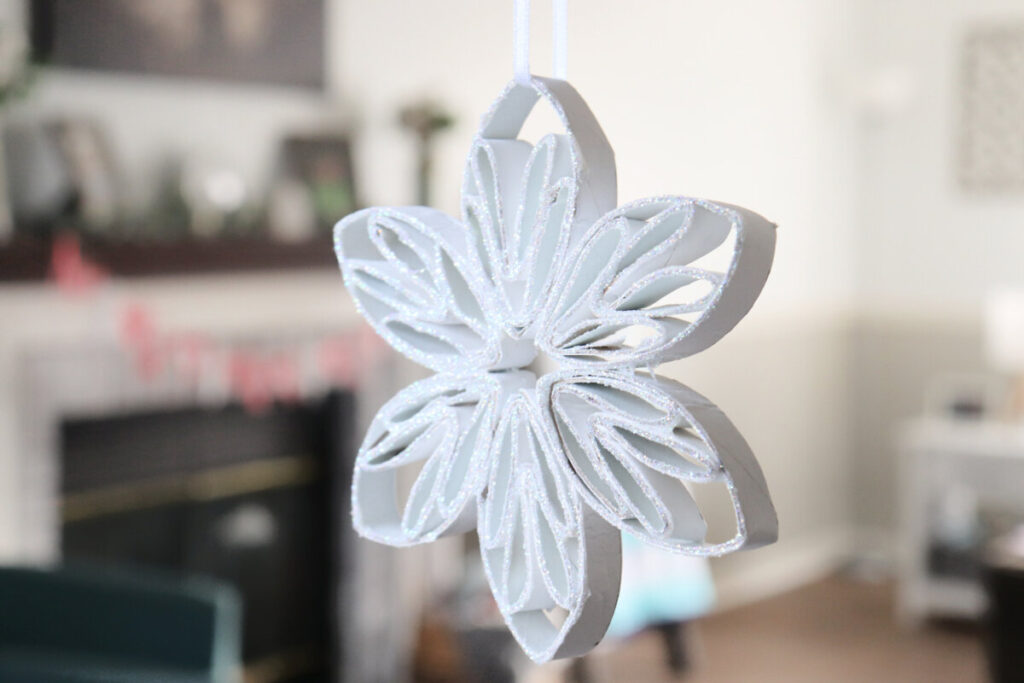 Image contains a glittering white six-sided snowflake made from a craft roll.
