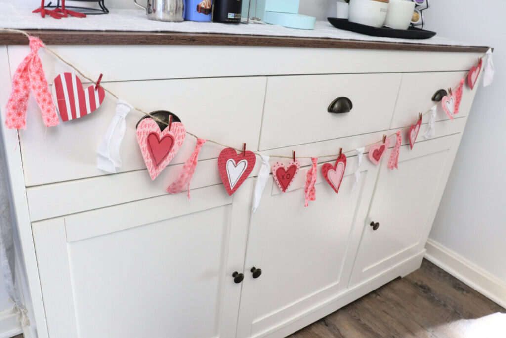 Image contains a white coffee bar styled for Valentine’s Day with the finished banner project draped across the front.