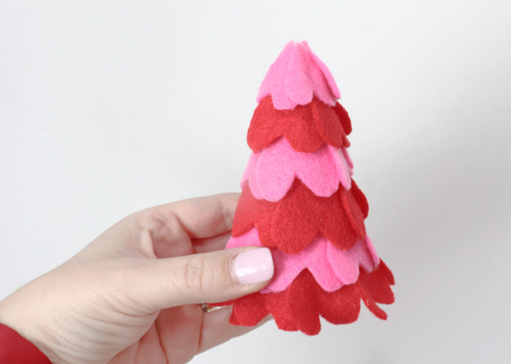 Image contains Amy’s hand holding a styrofoam cone covered in pink and red felt hearts.