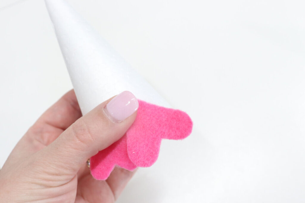 Image contains Amy’s hand holding a styrofoam cone with two pink felt hearts attached to the bottom.