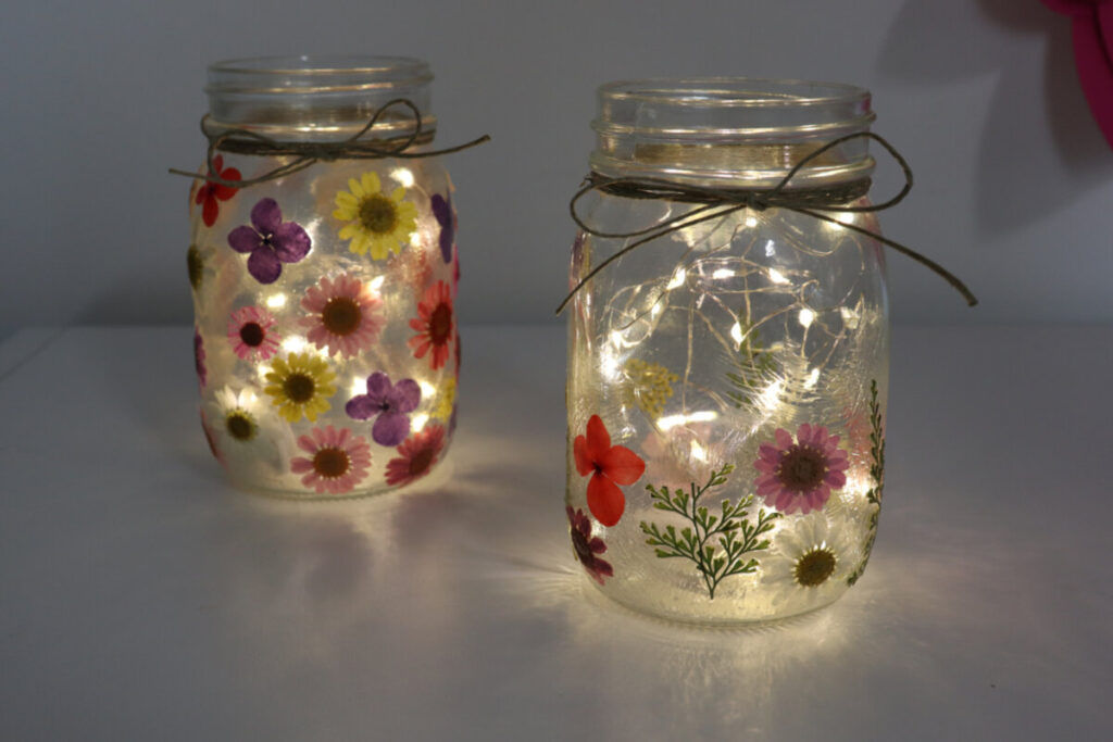 Image contains two lit pressed flower lanterns in a dark room.