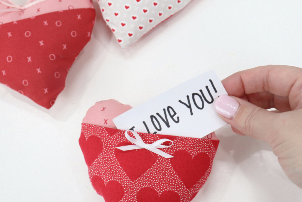 Image contains Amy’s hand sliding a note that reads, “I love you,” into the pocket of the plush heart.