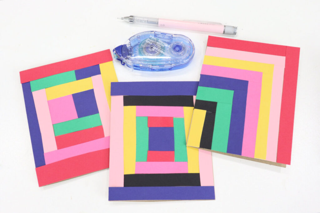 Image contains three finished quilt inspired cards, an adhesive runner, and a mechanical pencil on a white tabletop.
