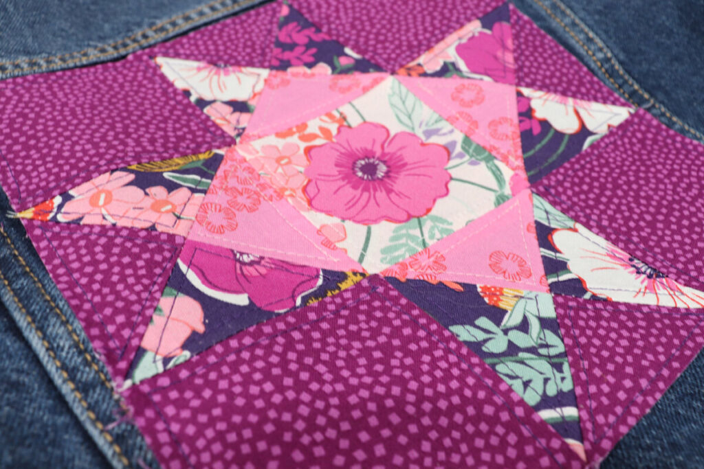 Image is a close-up view of the Ohio Star Quilt block in pink and purple fabrics, with decorative stitching added.