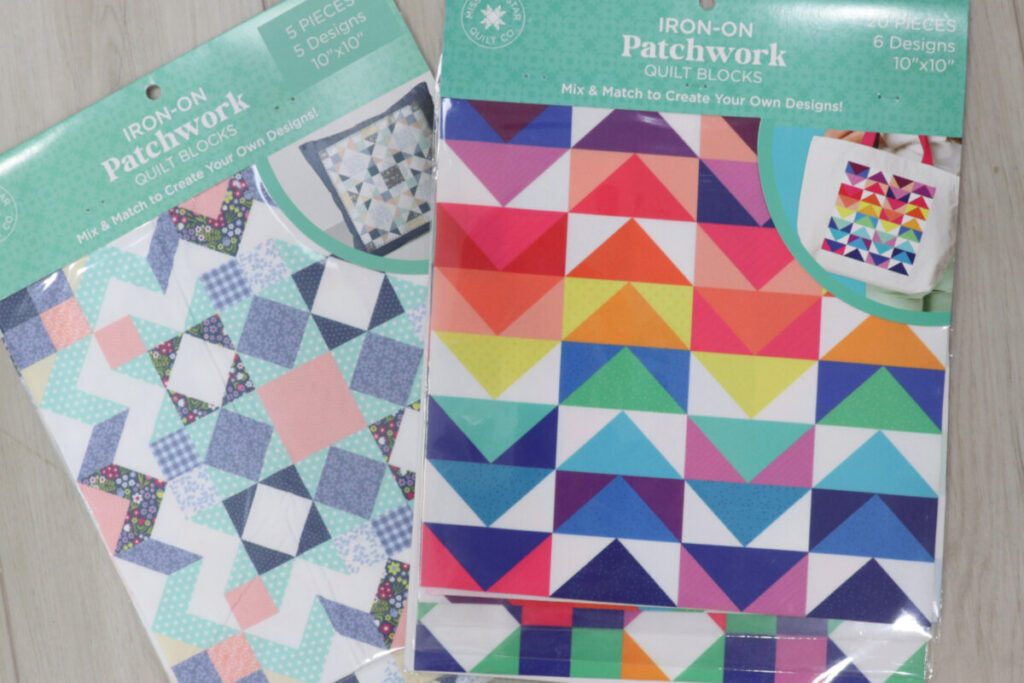 Image contains two packages of MSQC Iron On Patchwork Quilt Blocks; one Cottage Core, and one Brights, on a wooden background.
