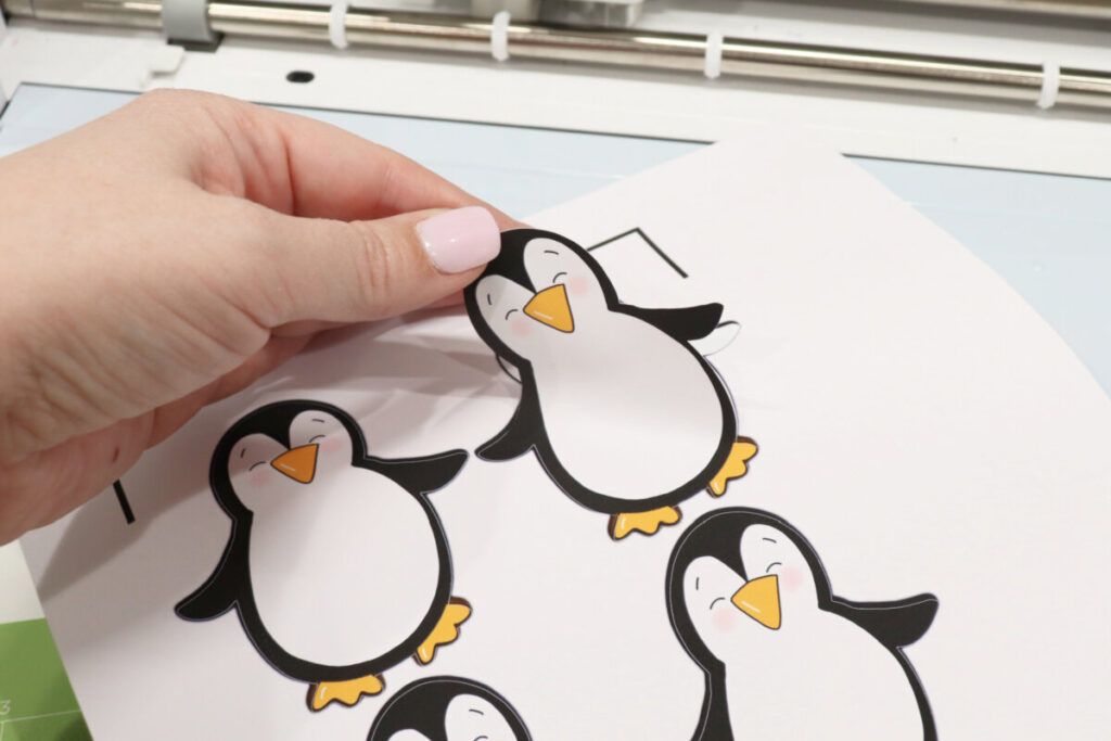 Image contains Amy’s hand peeling a penguin sticker away from its backing.