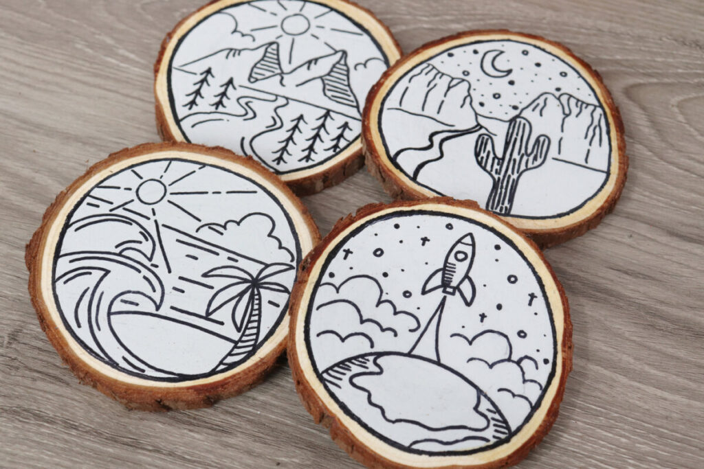 Image contains four round wooden coasters, each decorated with a monoline travel scene.