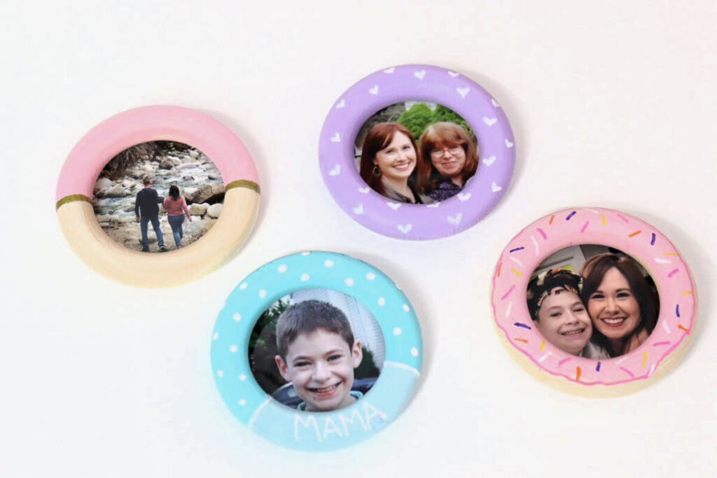 Image contains four wooden ring photo magnets painted with a variety of pink, purple, and teal designs.