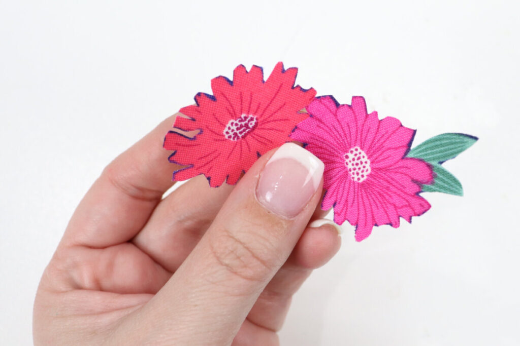 Image contains Amy’s hand holding two fabric flower appliques.