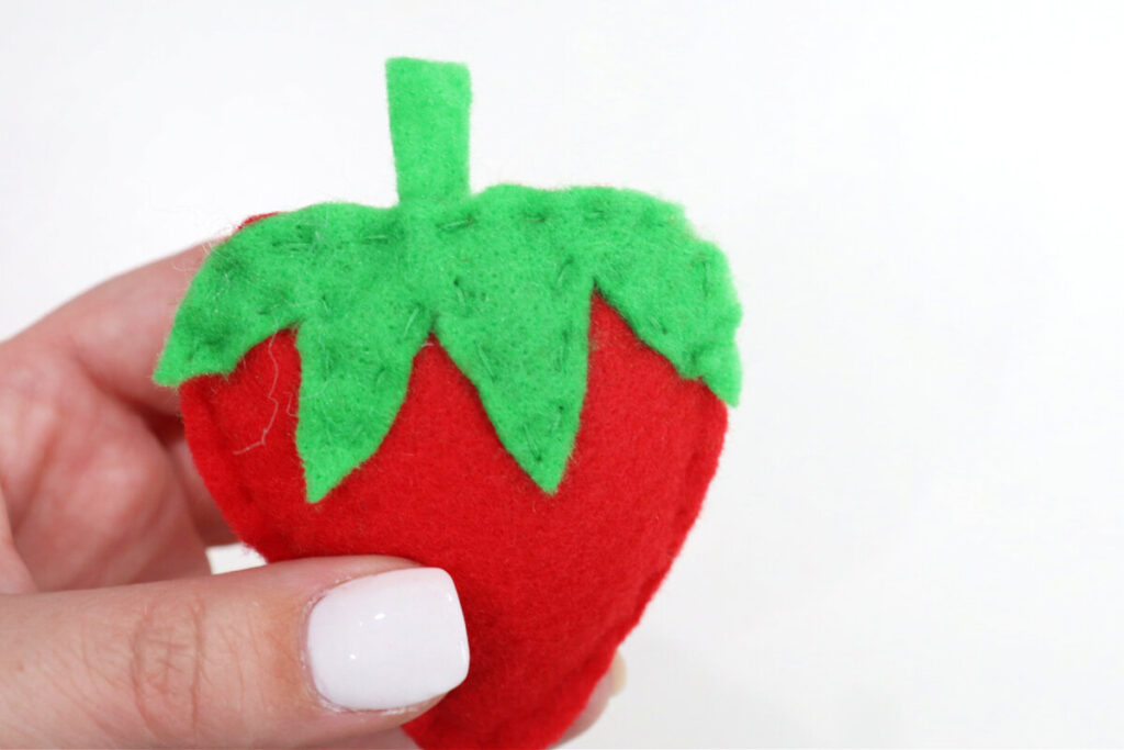 Image contains Amy’s hand holding a plush felt strawberry.