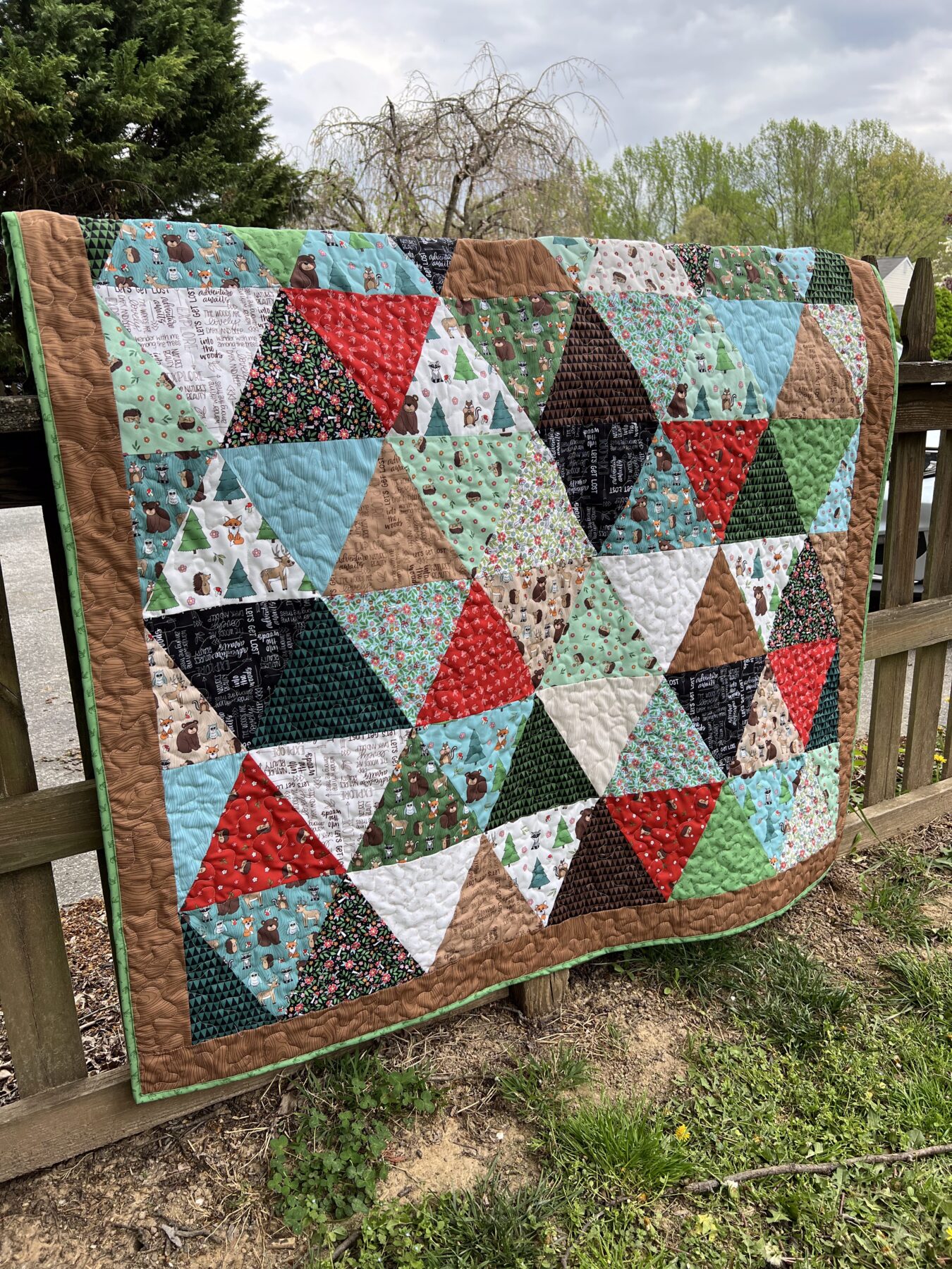 Image contains a quilt made of alternating triangles in a woodsy fabric collection.