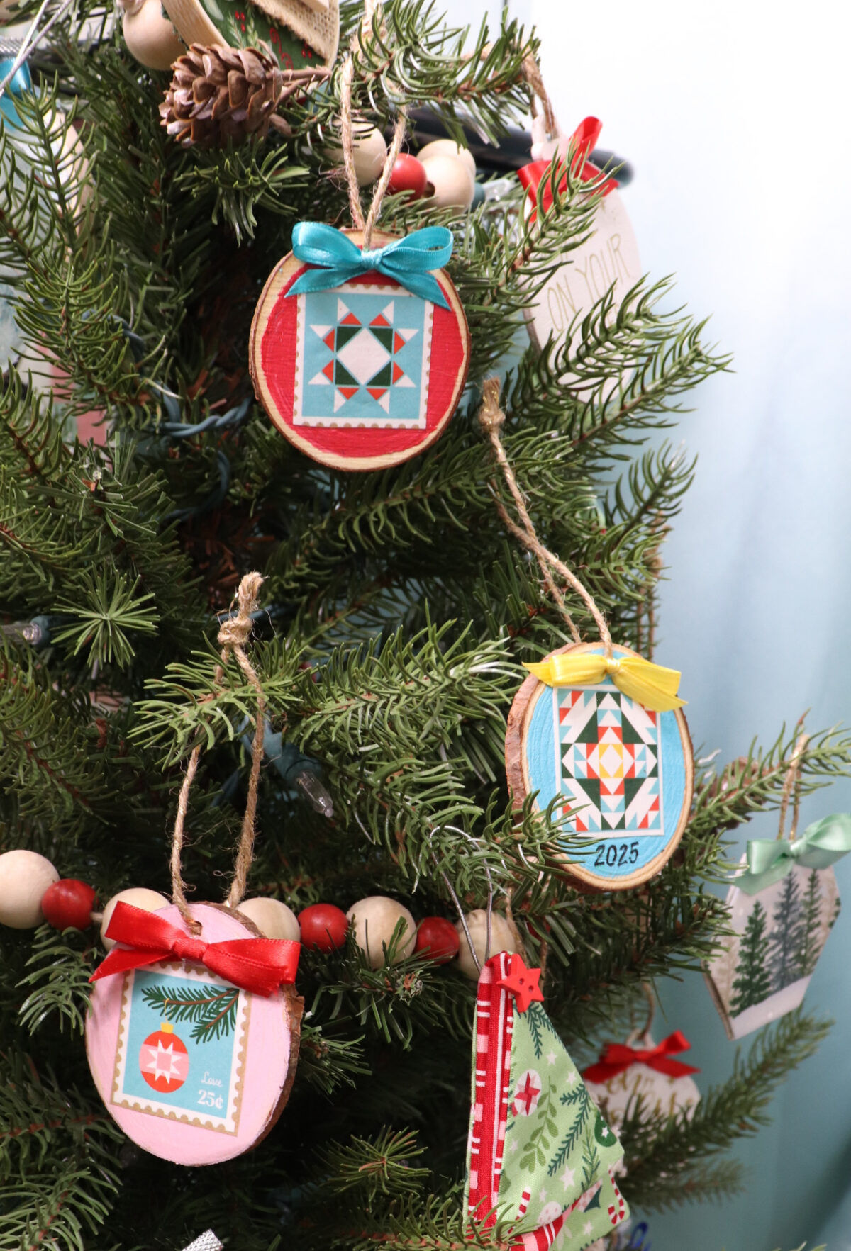 Image contains multicolored ornaments hanging on an artificial Christmas tree.