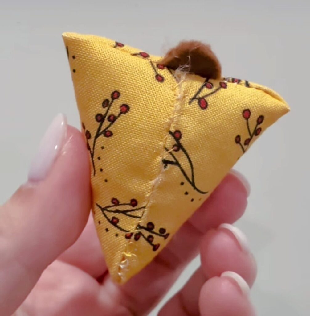 Image shows Amy’s hand holding the chicken body with visible hand stitching along the bottom seam.