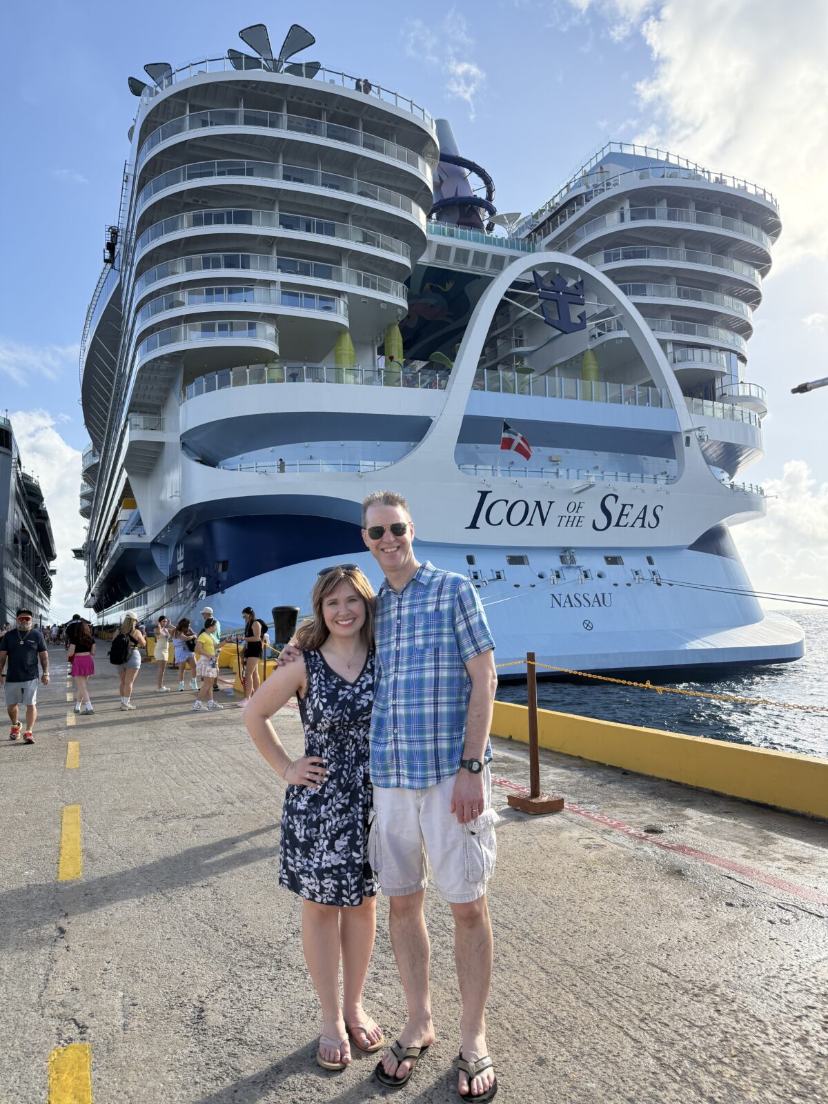 Image contains a man and woman standing in front of the Icon of the Seas cruise ship.