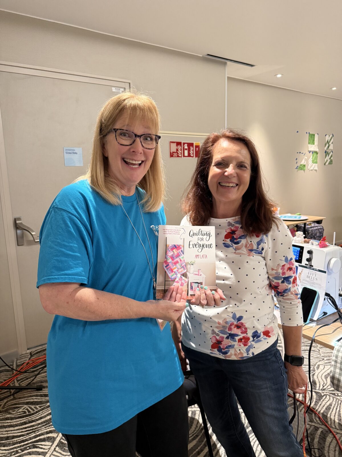 Image contains two smiling women holding a book, Quilting for Everyone.