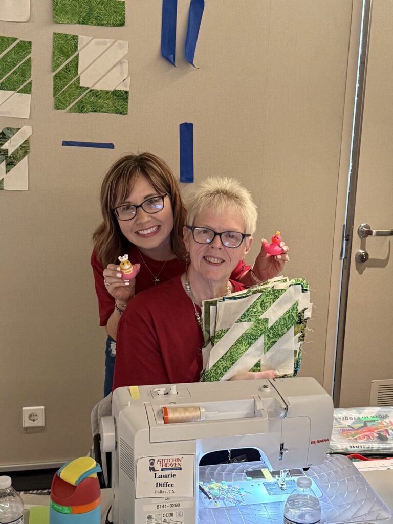 Image contains two smiling women at a sewing machine.