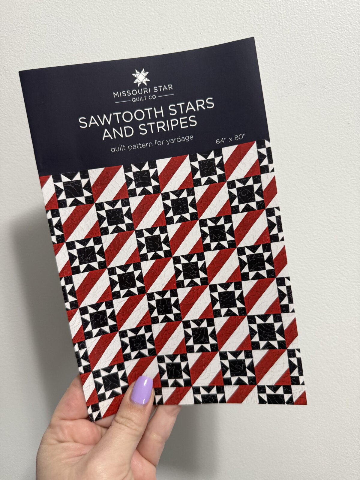 Image contains Amy’s hand holding a printed copy of the Sawtooth Stars and Stripes quilt pattern by Missouri Star Quilt Company.