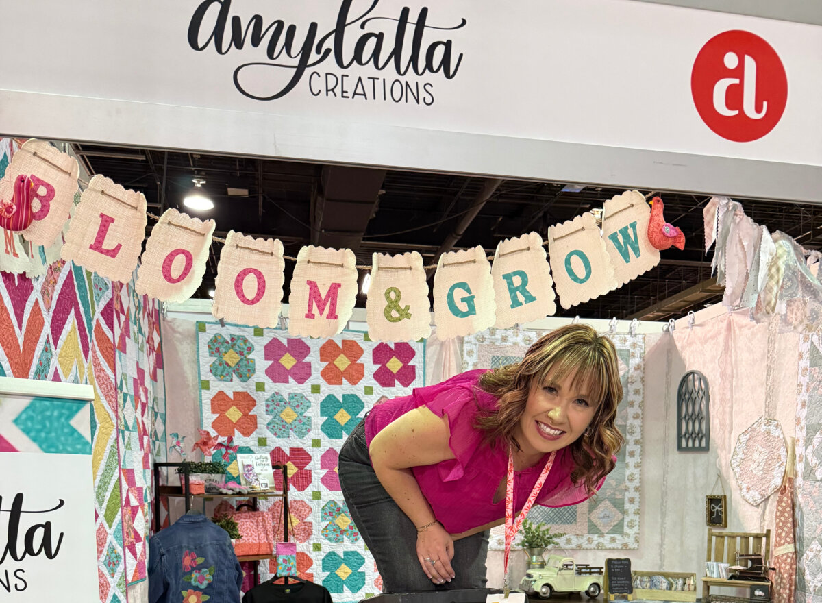 Image contains Amy hanging the banner in her booth at h+h.