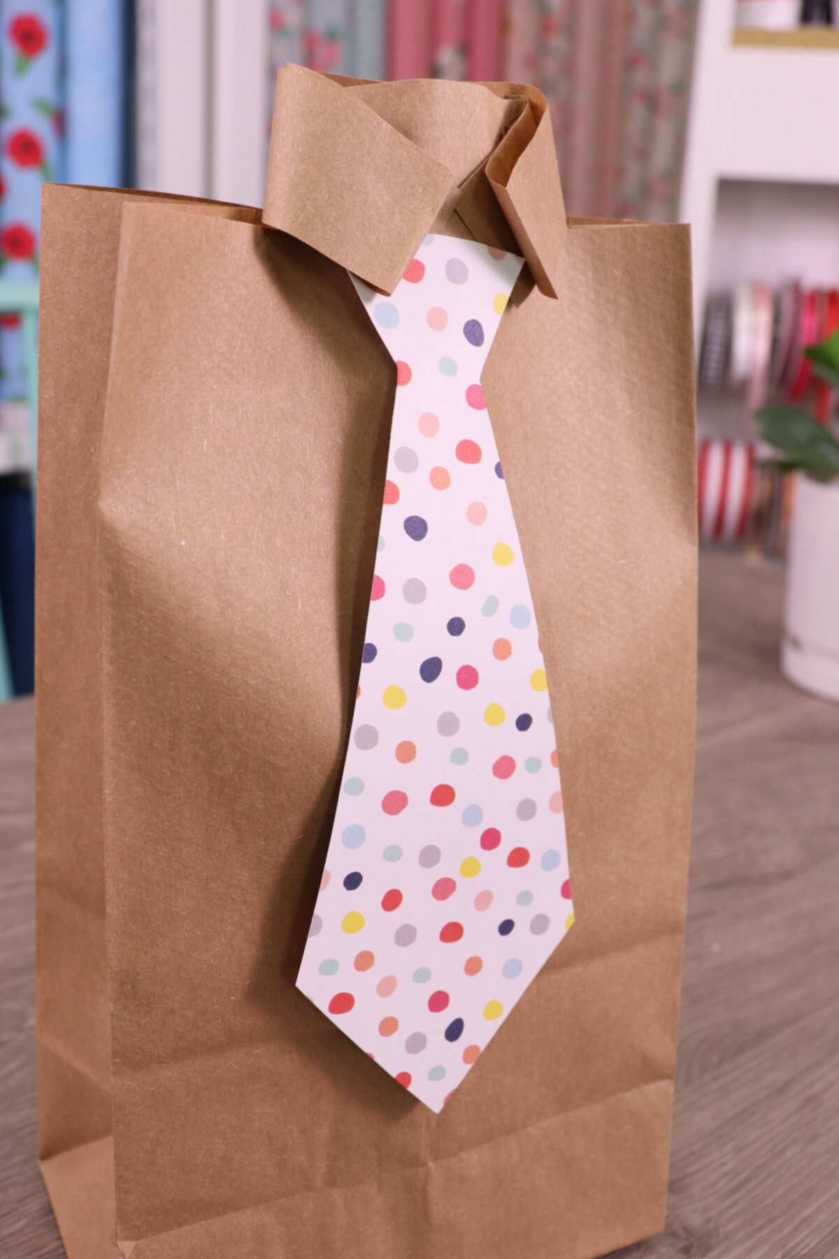 Image contains a paper bag folded to look like a dress shirt with a polka dot tie.