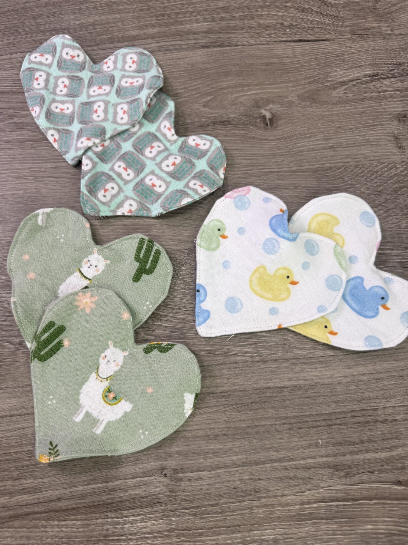 Image contains six hearts made of pattened flannel on a wooden table.