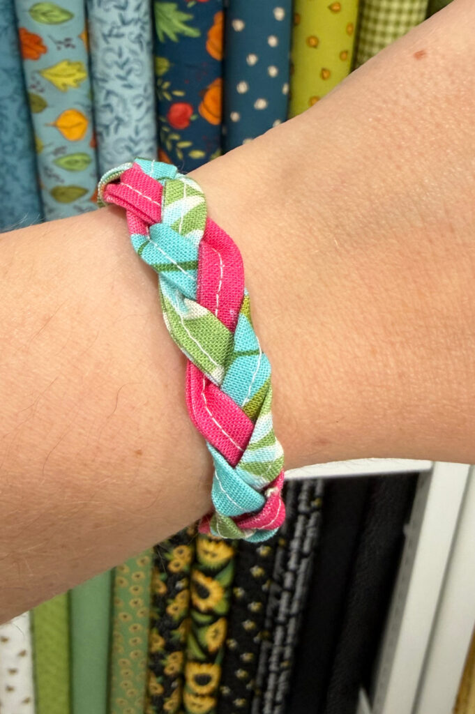 Image contains the completed braided fabric bracelet on Amy’s arm