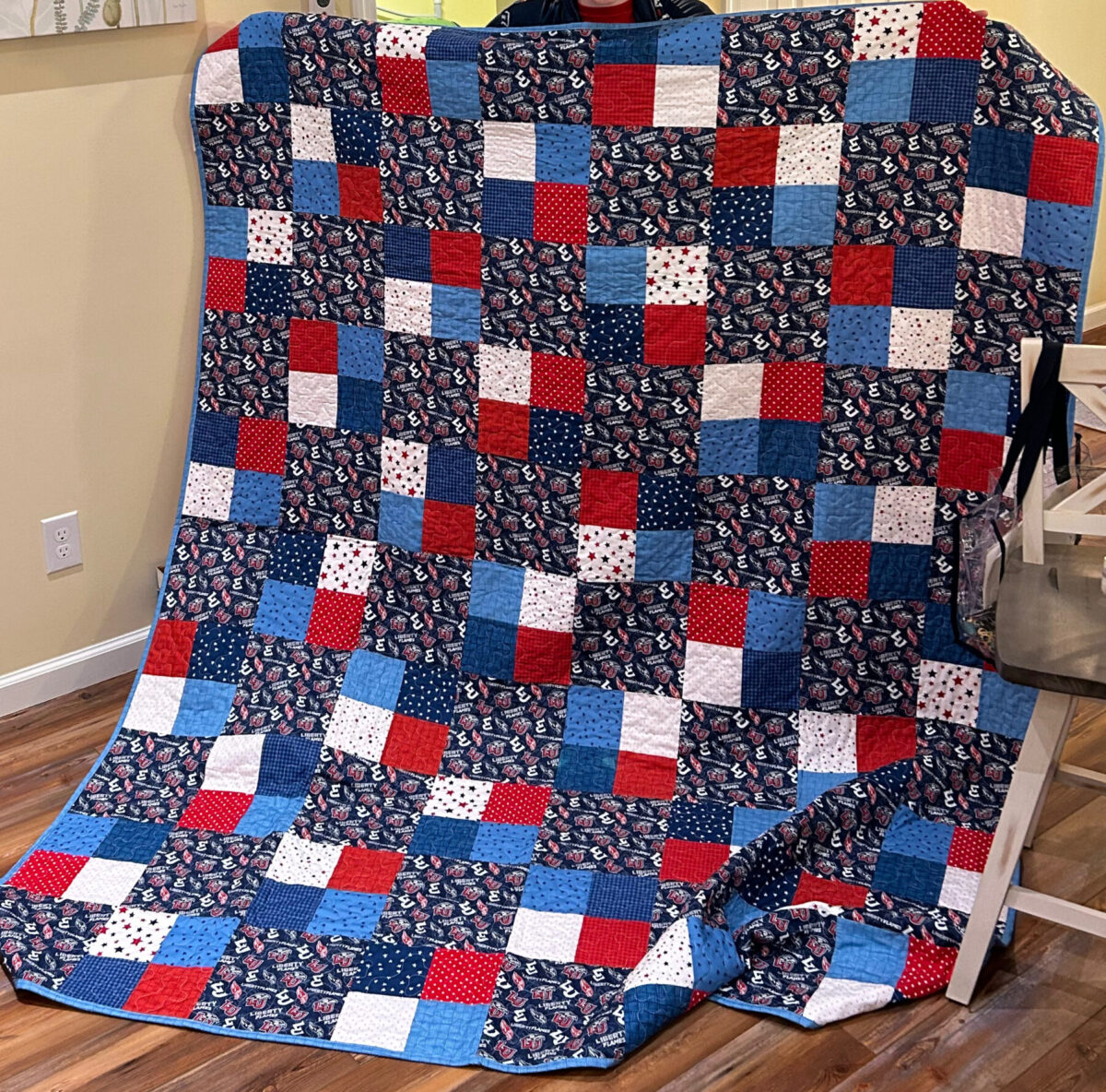 Image contains an alternating 4-patch quilt made of red, white, and blue fabrics.