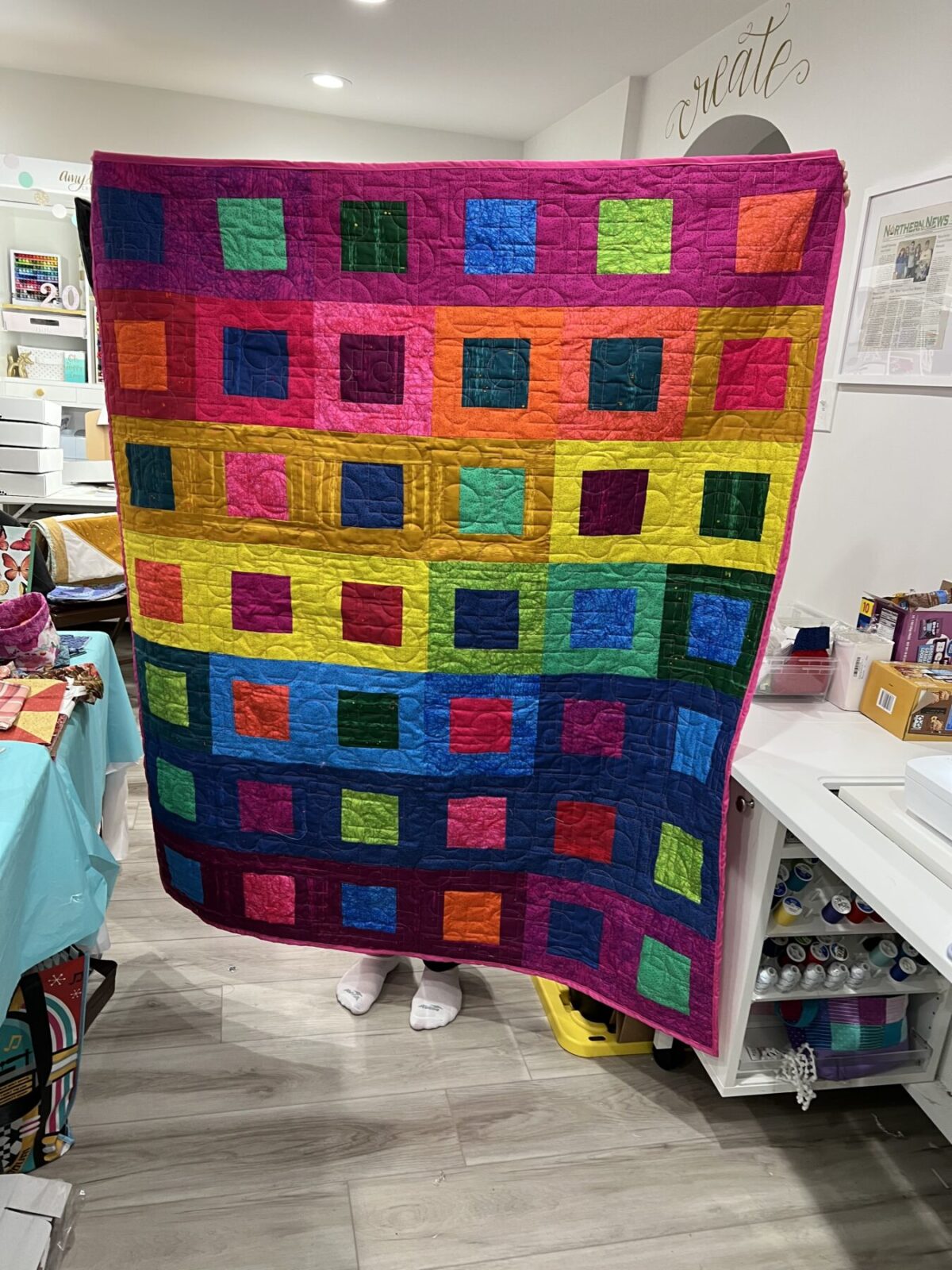 Image contains a vibrant quilt made of smaller squares inside larger ones.